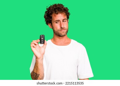 Young Caucasian Man Holding Car Keys Isolated Confused, Feels Doubtful And Unsure.