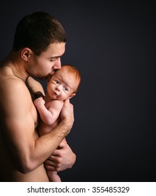 Young Caucasian Man Holding Little Son Over Black Background