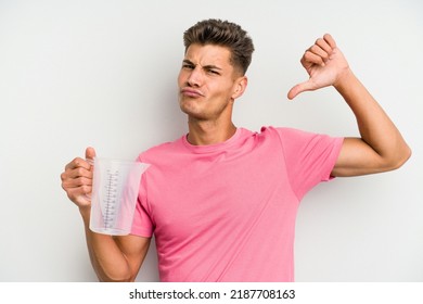 Young Caucasian Man Holding Measuring Jug Isolated On White Background Feels Proud And Self Confident, Example To Follow.