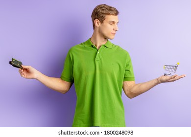 Young Caucasian Man Holding Toy Truck In One Hand And Wallet In Other, Going To Shop, Choose Between Shopping And Economy