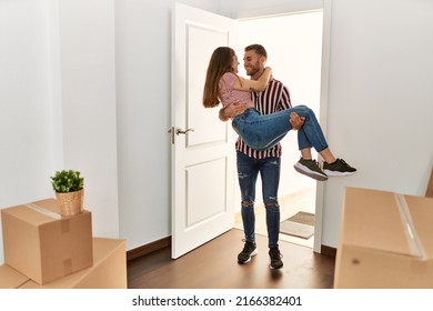 Young Caucasian Man Holding Woman In Arms Gettin In New Home Door.