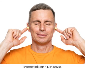 Young Caucasian Man Inserting Earplugs Into His Ears Over White Background