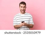 Young caucasian man isolated on pink background surprised and sending a message