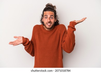 Young caucasian man isolated on gray background confused and doubtful shrugging shoulders to hold a copy space.