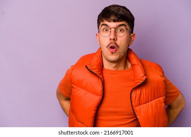 Young caucasian man isolated on purple background being shocked because of something she has seen.