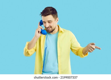 Young Caucasian man isolated on blue studio background talk on landline telephone. Male client have conversation on corded phone with customer service support. Telecommunication concept. - Powered by Shutterstock