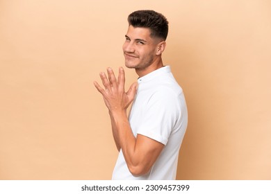 Young caucasian man isolated on beige background scheming something