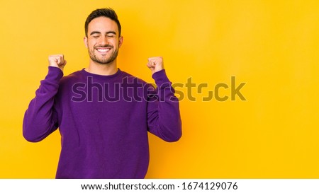Young caucasian man isolated on yellow bakground celebrating a victory, passion and enthusiasm, happy expression.