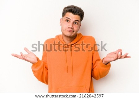 Young caucasian man isolated on white background doubting and shrugging shoulders in questioning gesture.
