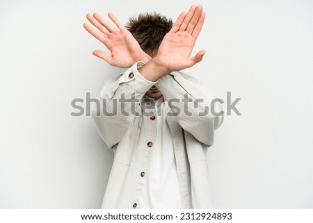 Young caucasian man isolated on white background keeping two arms crossed, denial concept.