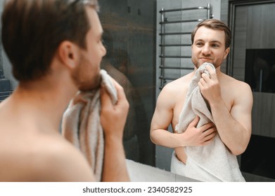 Young Caucasian man look in mirror do skincare facial routine after shower in home bathroom, millennial male in towel after bath apply face lotion or cream on skin after shaving, hygiene concept - Shutterstock ID 2340582925