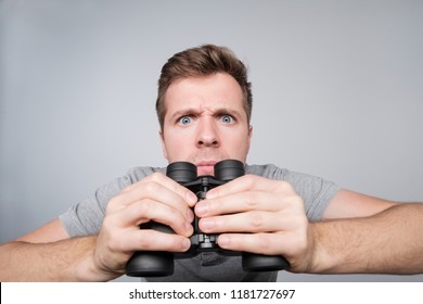Young Caucasian Man Looking With Binocular Ahead Trying To See Some Important Details. He Saw His Wife With Lover And Is Very Angry Now