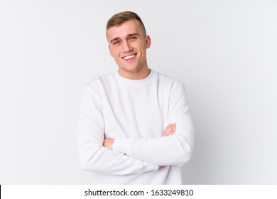 Young caucasian man on white background who feels confident, crossing arms with determination.