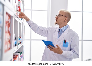 Young Caucasian Man Pharmacist Using Touchpad Holding Medicine Bottle At Pharmacy