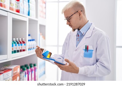 Young Caucasian Man Pharmacist Using Touchpad Holding Medicine Bottle At Pharmacy