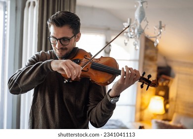 Young caucasian man playing violin at home. Hobby quality time happiness concept. - Powered by Shutterstock