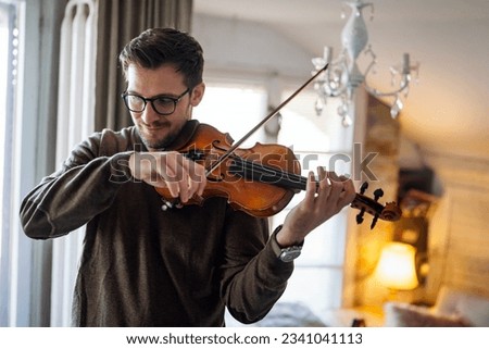 Young caucasian man playing violin at home. Hobby quality time happiness concept.