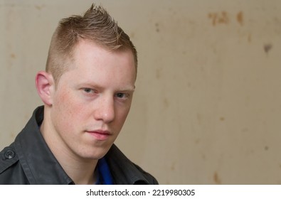 Young Caucasian Man Portrait With Spiky Hair Looking At Camera Grungy Out Of Focus Background, Rebel Concept