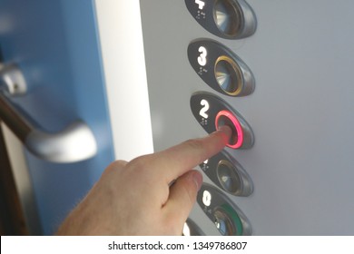 Young Caucasian Man Pressing Red Button Of Second Floor In An Elevator. Going Upstairs Concept. Hand Close Up. 