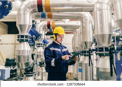 Young Caucasian man in protective suit using tablet while standing in heating plant. - Powered by Shutterstock