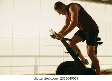 Young Caucasian man pushing himself to new limits on his state-of-the-art exercise bike, using the latest in fitness technology to achieve his health and fitness goals in the gym. - Powered by Shutterstock