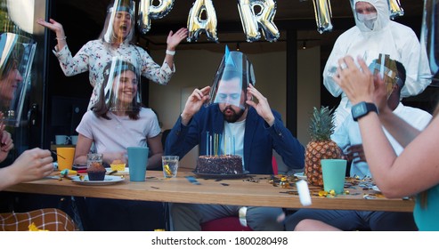 Young Caucasian man shares crazy fun celebration with friends, confetti and masks at COVID-19 birthday party slow motion