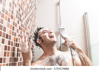 Young Caucasian man, singing and gesturing happily full of soap in the bathroom shower.