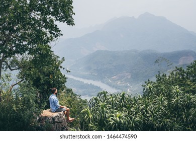 Young Caucasian man sits on the top of the mountain overlooking river valley in Nong Khiaw village, Laos - Shutterstock ID 1464474590