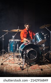Young Caucasian man sitting at drum set in studio. Rock musician training or rehearsing in garage. Drummer training concept