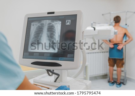 Young caucasian man standing against wall while doctor using X-Ray machine scan him in hospital