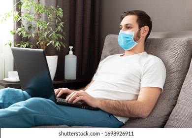 Young caucasian man stay home working from home wearing protective mask using laptop and internet. Cozy Home office, workplace on sofa coronavirus pandemic, covid 19 quarantine. Remote work,freelancer - Powered by Shutterstock