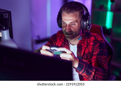 Young Caucasian Man Streamer Playing Video Game Using Joystick At Gaming Room