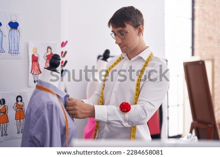 Young caucasian man tailor measuring shirt at tailor shop
