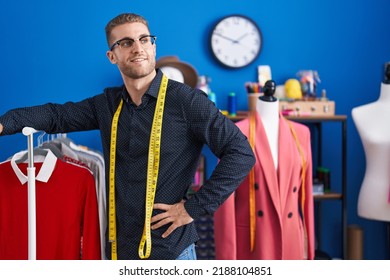 Young Caucasian Man Tailor Smiling Confident Leaning On Clothes Rack At Clothing Factory