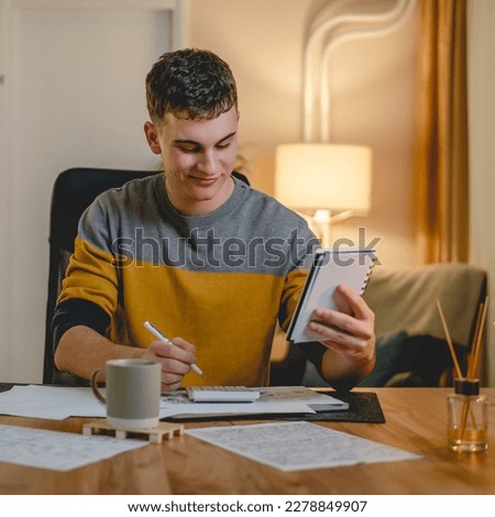 Young caucasian man teenager student study at home at the table at night or evening determinate learning prepare lesson or exam alone real people copy space Foto stock © 