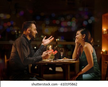 Young Caucasian man telling funny stories to his Vietnamese girlfriend during romantic date