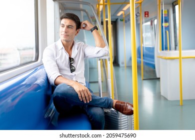 Young Caucasian Man Traveler Holding Luggage Sitting Inside Empty Subway Or Sky Train Car.  