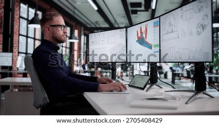 Young Caucasian Man Using Computer To Design Mechanical Product In 3D CAD Model