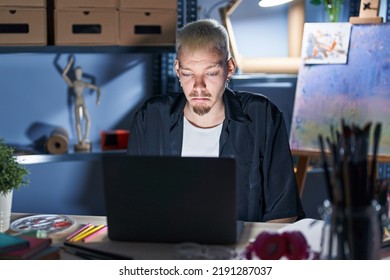 Young Caucasian Man Using Laptop At Night At Art Studio Depressed And Worry For Distress, Crying Angry And Afraid. Sad Expression. 