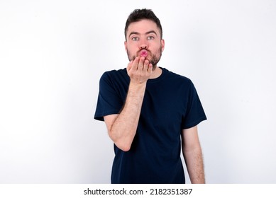 Young Caucasian Man Wearing Black T-shirt Over White Background Looking At The Camera Blowing A Kiss With Hand On Air Being Lovely And Sexy. Love Expression.