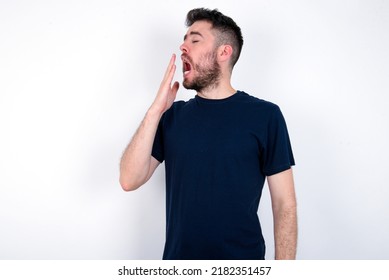 Young Caucasian Man Wearing Black T-shirt Over White Background Being Tired And Yawning After Spending All Day At Work.