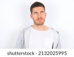 young caucasian man wearing casual clothes over white background has worried face looking up lips together, being upset thinking about something important, keeps hands down.