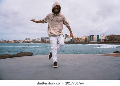 Young caucasian man, wearing casual clothes, dancing urban dances on the beach avenue
