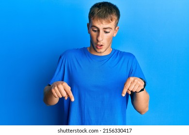 Young Caucasian Man Wearing Casual Blue T Shirt Pointing Down With Fingers Showing Advertisement, Surprised Face And Open Mouth 