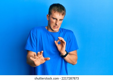 Young Caucasian Man Wearing Casual Blue T Shirt Disgusted Expression, Displeased And Fearful Doing Disgust Face Because Aversion Reaction. 