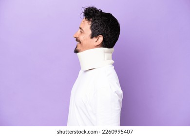 Young caucasian man wearing neck brace isolated on purple background looking side - Powered by Shutterstock