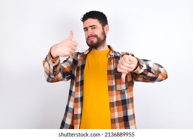 Young Caucasian Man Wearing Plaid Shirt Over White Background Feeling Unsure Making Good Bad Sign. Displeased And Unimpressed.