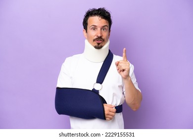 Young caucasian man wearing a sling and neck brace isolated on purple background intending to realizes the solution while lifting a finger up - Powered by Shutterstock