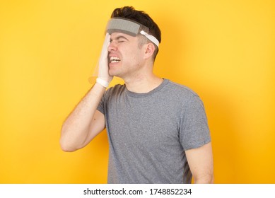 Young Caucasian Man Wearing T-shirt And Face Shield  Standing Over Isolated Yellow Background Yawning Tired Covering Half Face, Eye And Mouth With Hand. Face Hurts In Pain.