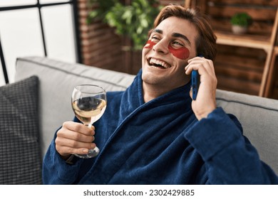 Young caucasian man wearing under eye patches talking on smartphone at home - Powered by Shutterstock